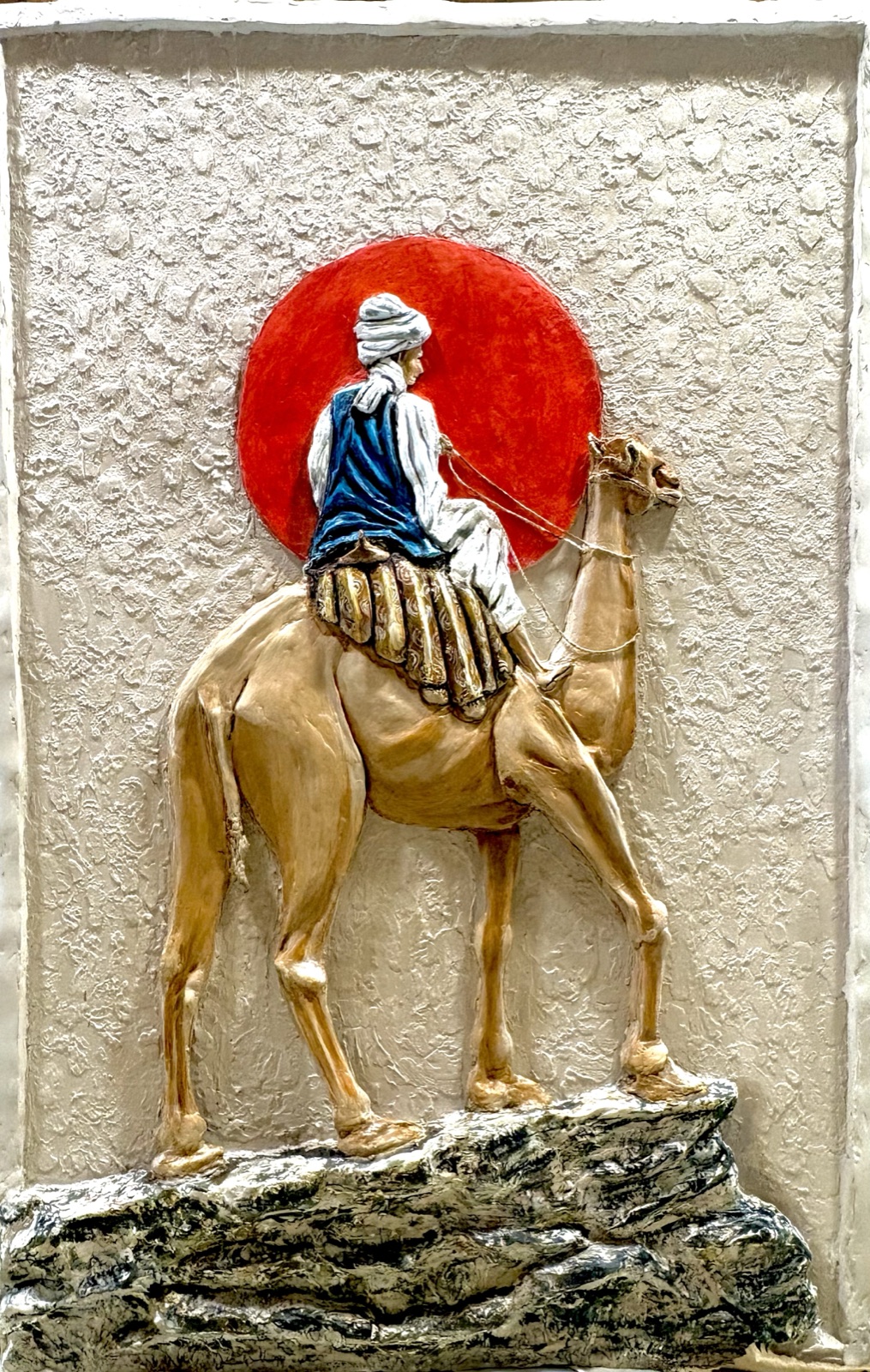 The Wanderer's Resolve — a relief mural of a lone camel rider before a red sun